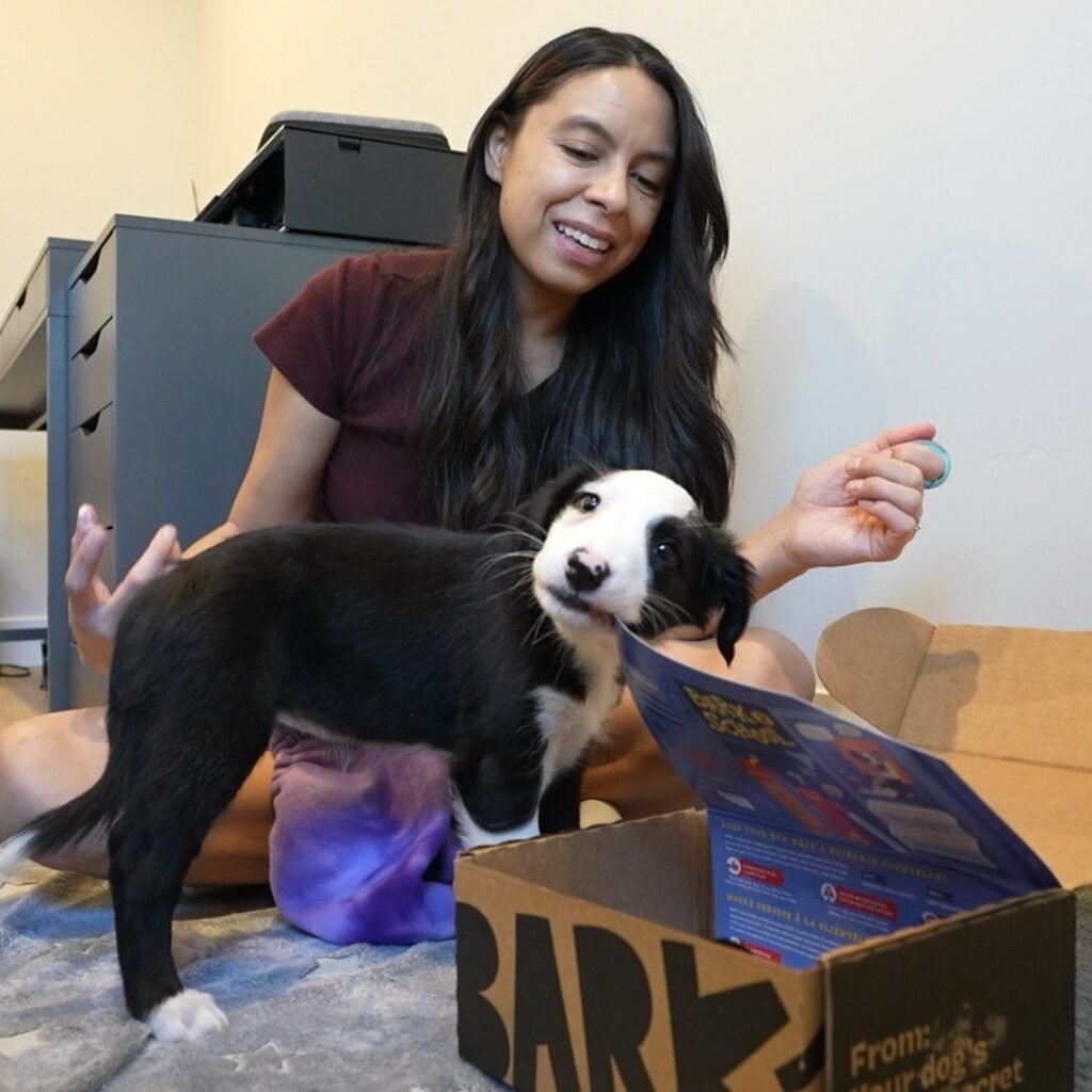 Happy woman playing with a small black and white puppy