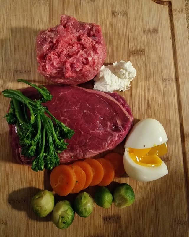 Raw meat, vegetables, and a soft-boiled egg on wood